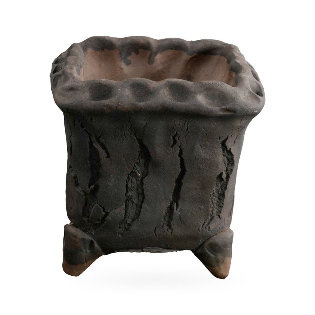 Rough matte charcoal-black square footed pot with cracked bark texture and dimpled rim