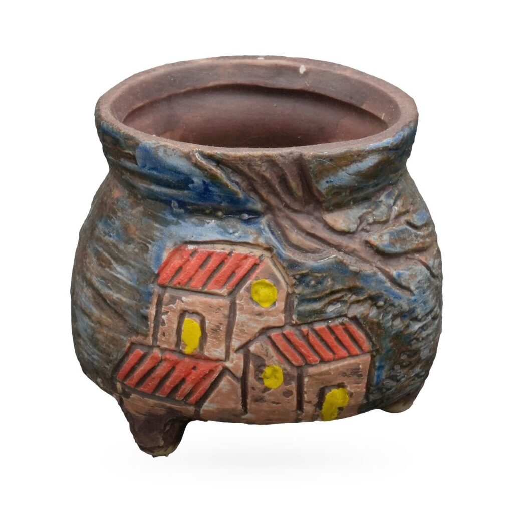 Small round brown and blue pot with raised painted red-roofed cottages and tree branches, on small feet