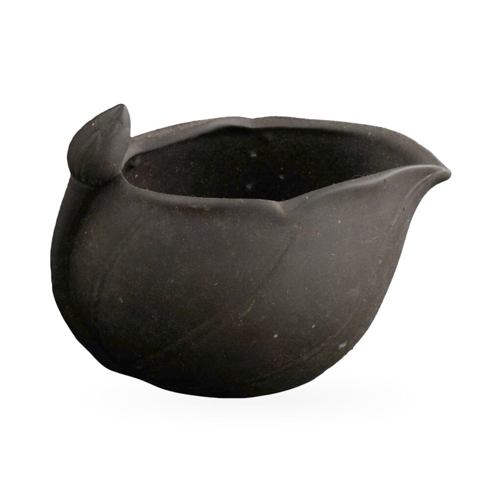 Small matte black unglazed clay pot shaped like a pitcher with a pointed spout and rounded knob