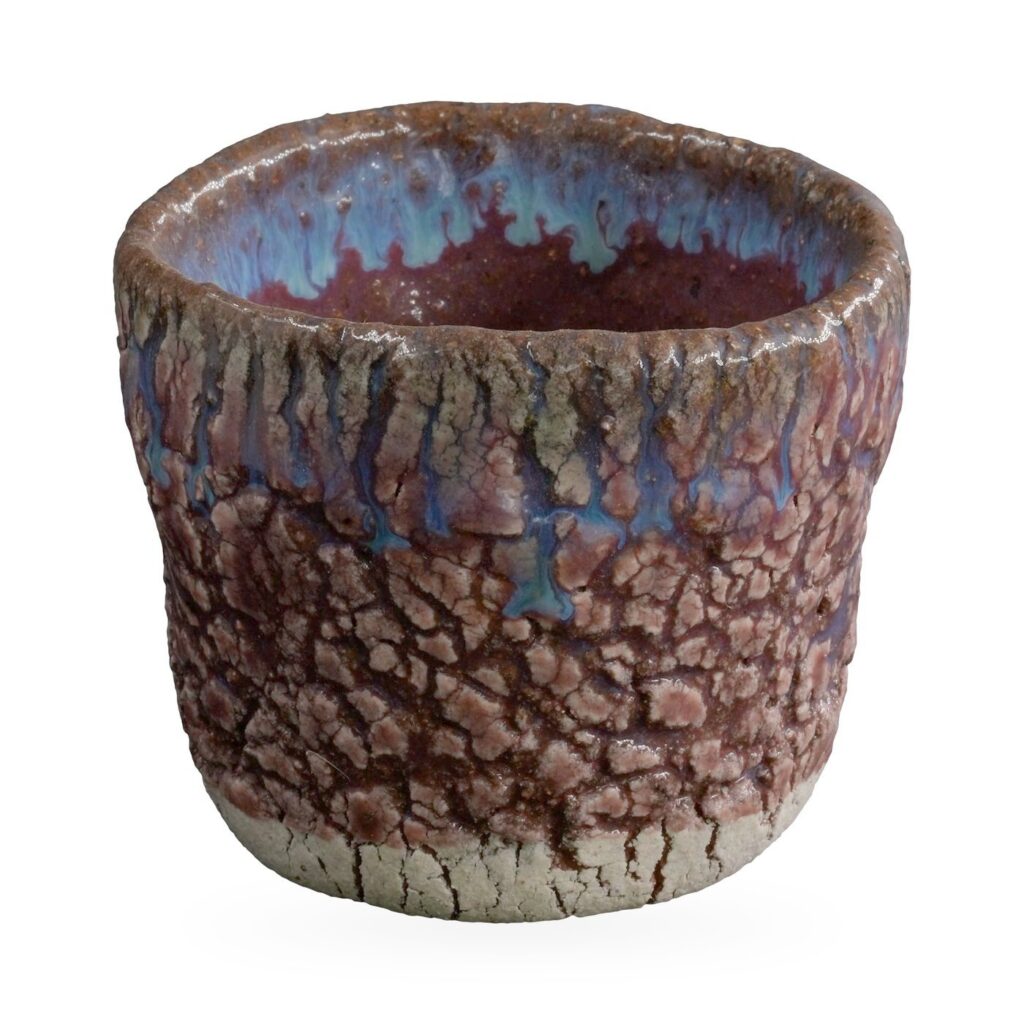 Round rustic pot with raised purple-pink crackle glaze and blue glaze drips at the rim