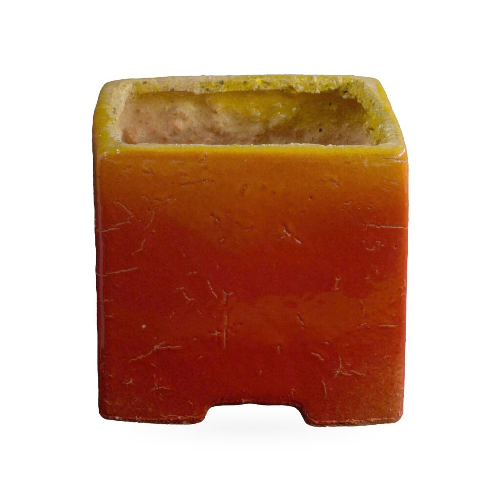 Glossy square pot fading from orange to red with a mustard-yellow rim and small corner feet