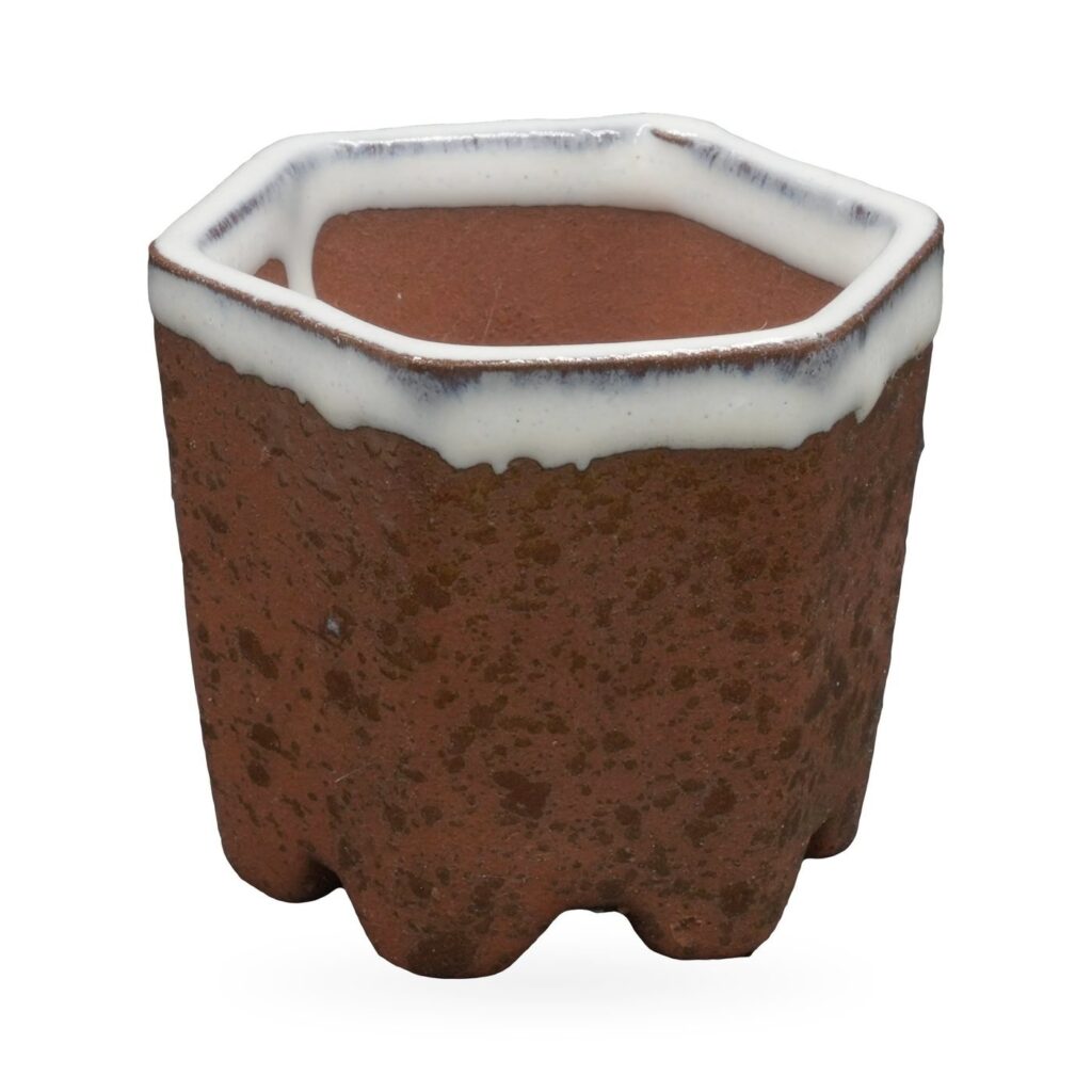 Speckled rust-brown hexagonal footed pot with glossy white drip glaze around the rim