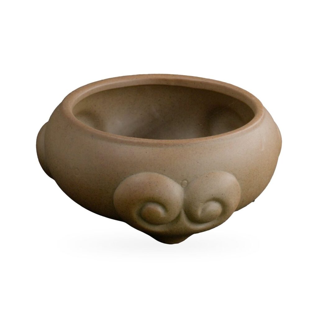 Low khaki tan succulent bowl with raised scroll-like swirl motifs that form its small feet