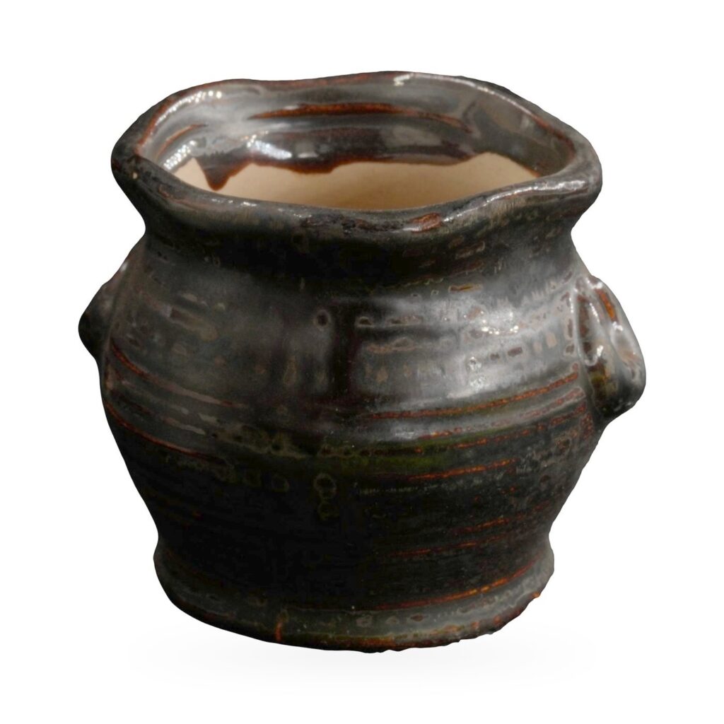 Small black-brown glazed rustic pot with textured body, wavy rim and two small loop ears