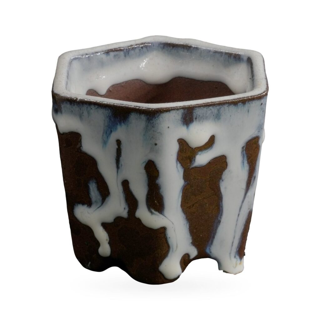 Hexagonal dark brown textured pot with thick white glaze dripping from the rim