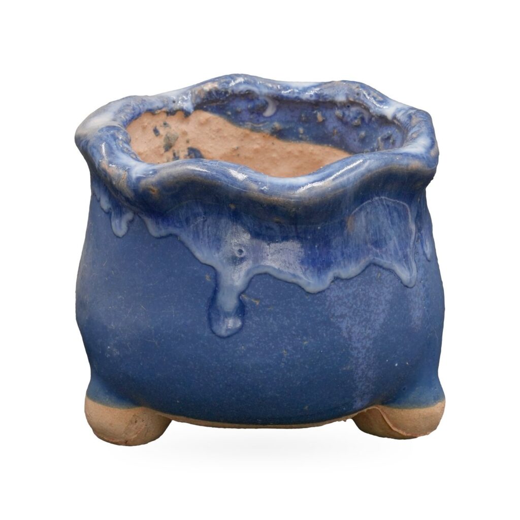 Cobalt blue footed pot with a wavy rim and glossy blue and white glaze drips from the rim